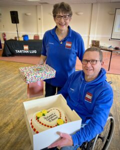 The happy couple holding an anniversary cake and gifts.